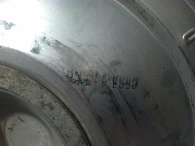 Close-up of stamped numbers on a metal part, possibly a hubcap or wheel cover
