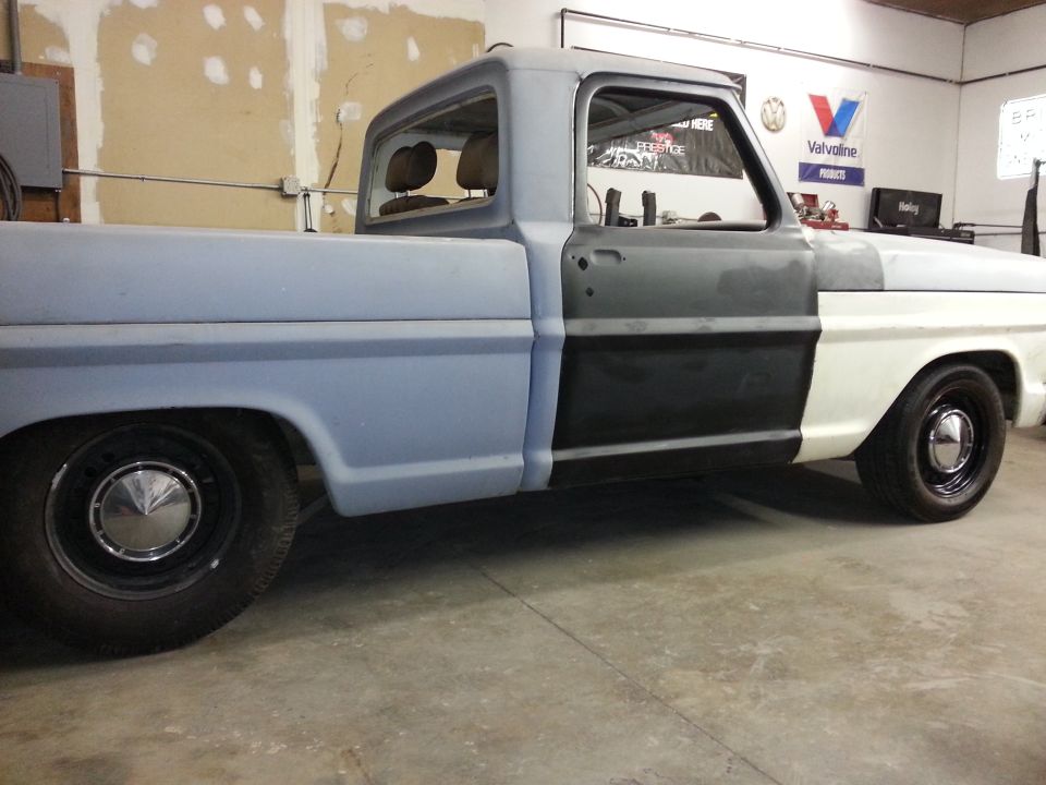 1967 Ford F-100 truck in primer and white, side view, undergoing restoration