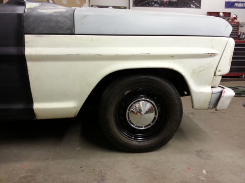 1967 Ford F-100 - Side view of a 1967 Ford F-100 truck fender and wheel, showing primer on the hood and two-tone paint.
