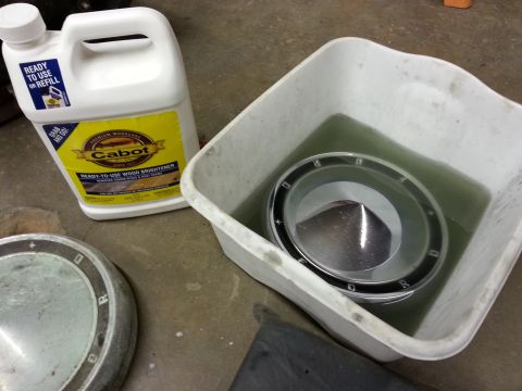 1967 Ford F-100 - Hubcap soaking in a tub with wood brightener. The word 'FORD' is visible on the hubcap.