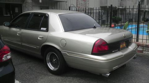 2000 Mercury Grand Marquis - A silver 2000 Mercury Grand Marquis sedan is parked outdoors, with a swimming pool visible in the background.
