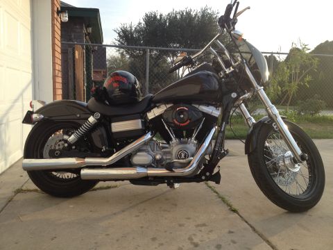 1995 Ford Bronco - A black Harley-Davidson motorcycle is parked on a concrete driveway next to a brick building.