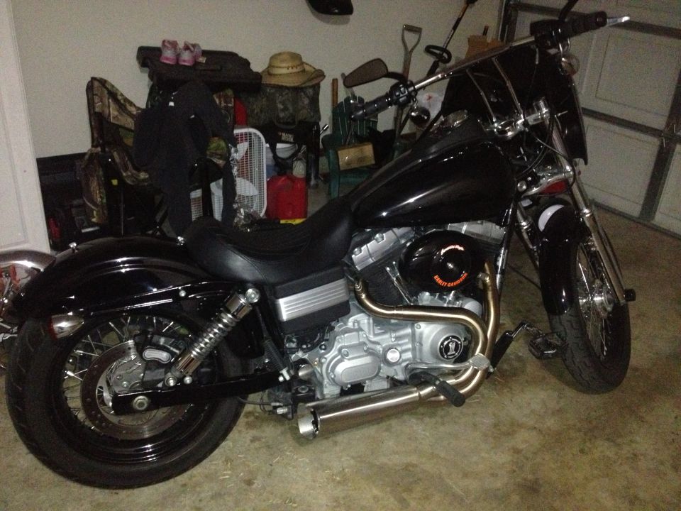 Black motorcycle parked in a garage, side view showing engine and exhaust