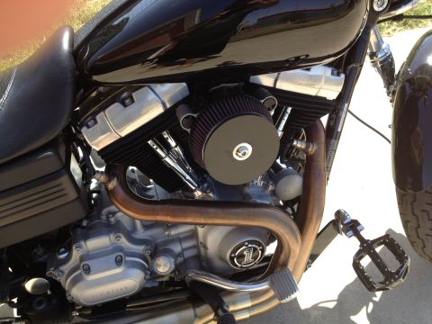 1995 Ford Bronco - Close-up view of a motorcycle's engine, a black air filter and copper exhaust pipes.