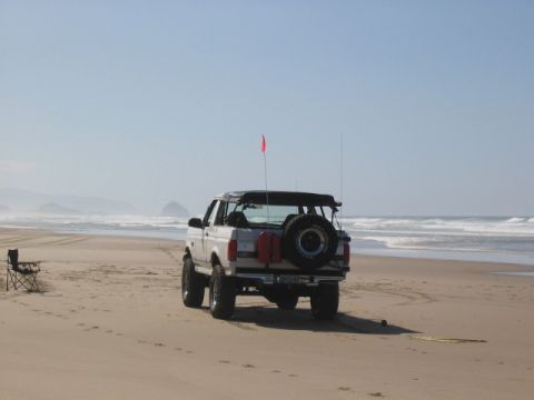 1995 Ford Bronco - Ford Bronco with spare tire on rear parked on beach near the ocean.