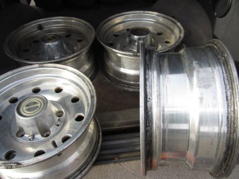 1995 Ford Bronco - A collection of four aluminum rims are shown, some stacked, in what appears to be the cargo area of a vehicle.