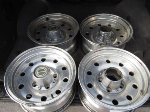 1995 Ford Bronco - Four aluminum alloy wheels are stored in the cargo area of a vehicle.