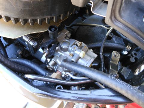 1996 Ford F-150 - A close-up view of a carburetor and associated engine components, including hoses and wiring.