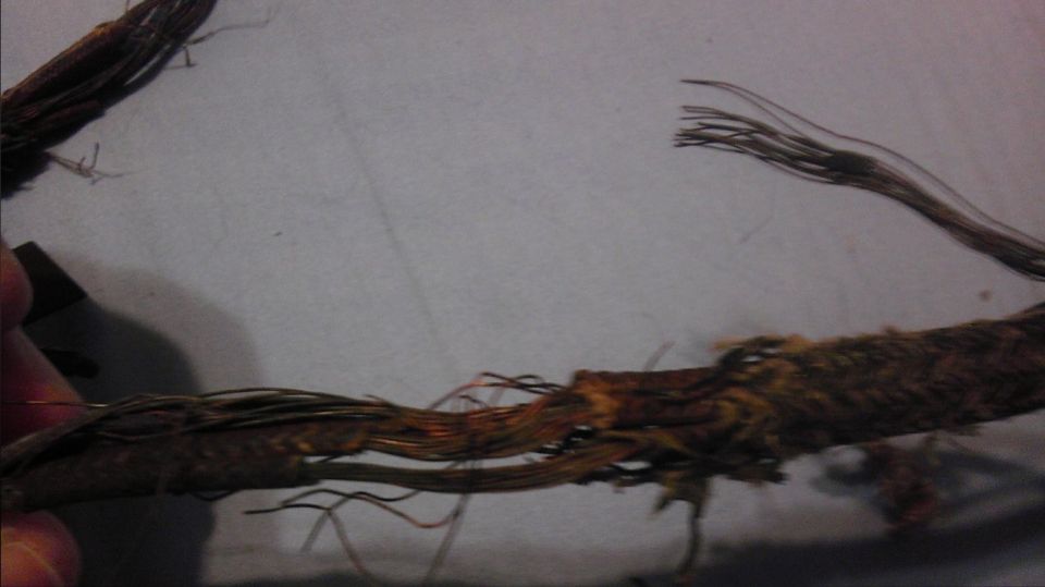 Damaged electrical wiring harness with frayed wires and exposed copper strands