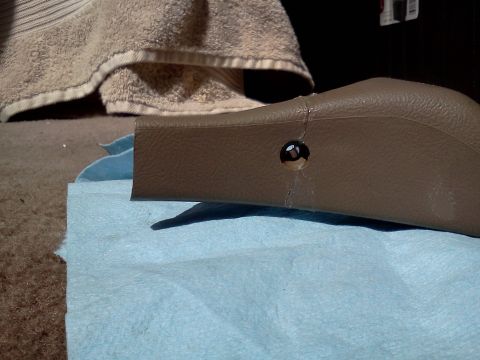 1995 Ford Bronco - A brown plastic trim piece with a visible screw hole rests on a blue paper towel.