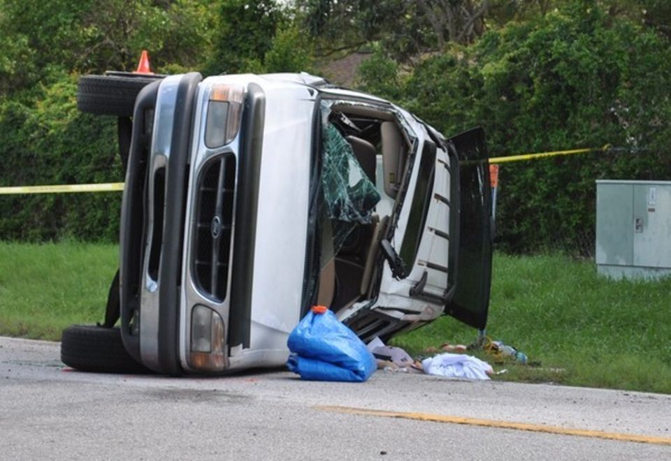 White SUV flipped on its side on the side of the road, windshield cracked