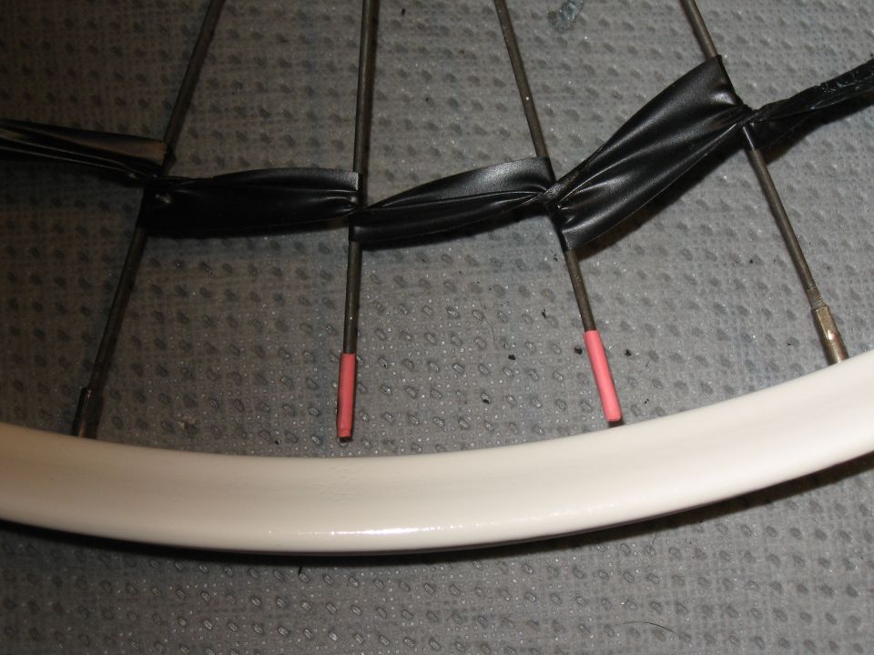 Bicycle wheel with spokes taped together and pink valve stem covers