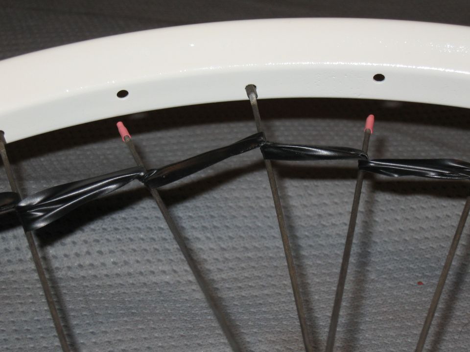 White bicycle wheel rim with spokes wrapped in black tape