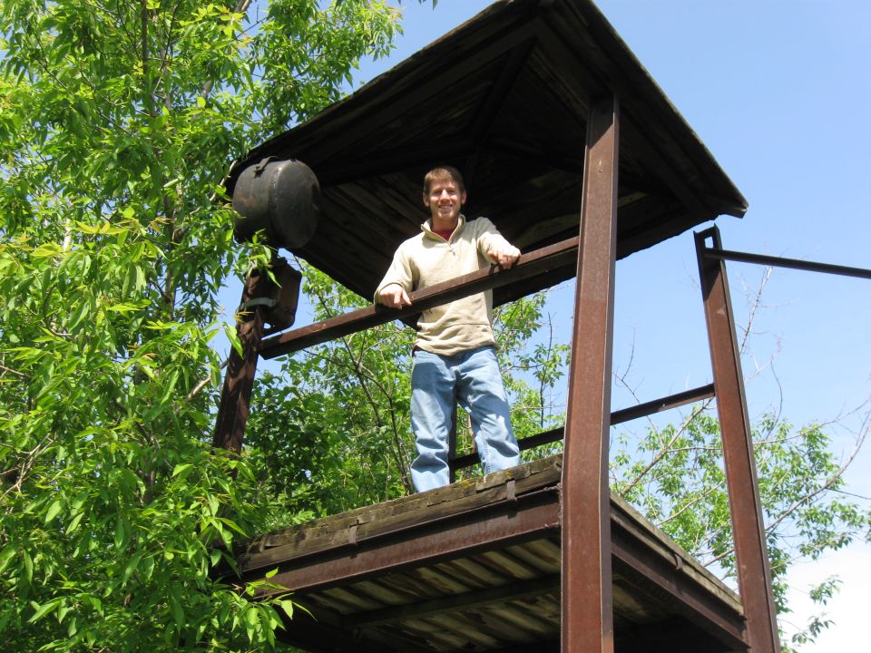 Man on a rustic wooden observation platform surrounded by trees