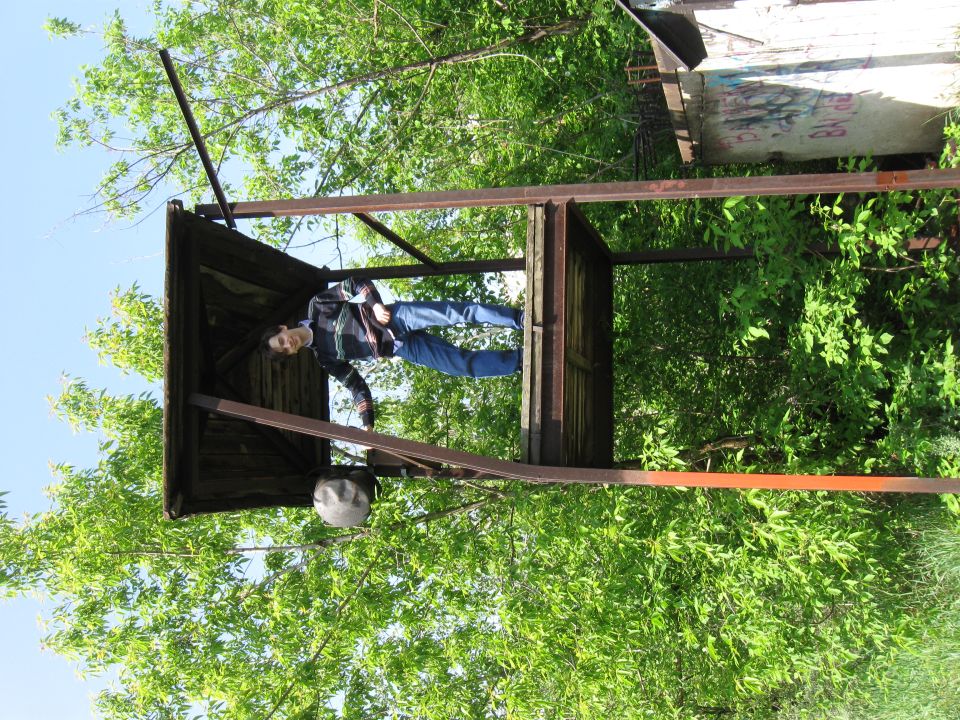Guy standing in a rickety wooden structure surrounded by trees