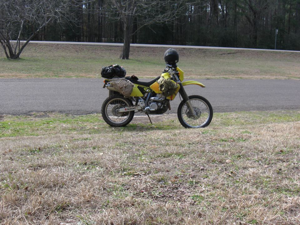 Yellow 2006 Suzuki DR-Z400S motorcycle parked on grass, loaded with saddlebags and a helmet on handlebars