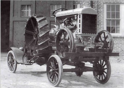 1909 Ford Model T - A vintage tractor with a large, spoked rear wheel and a smaller front wheel is shown from a three-quarter front angle.
