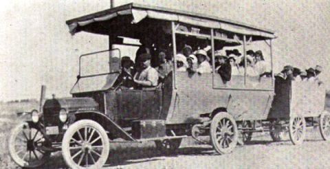 1909 Ford Model T - This early bus, likely from around 1910, has a distinctive body style and carries many passengers.