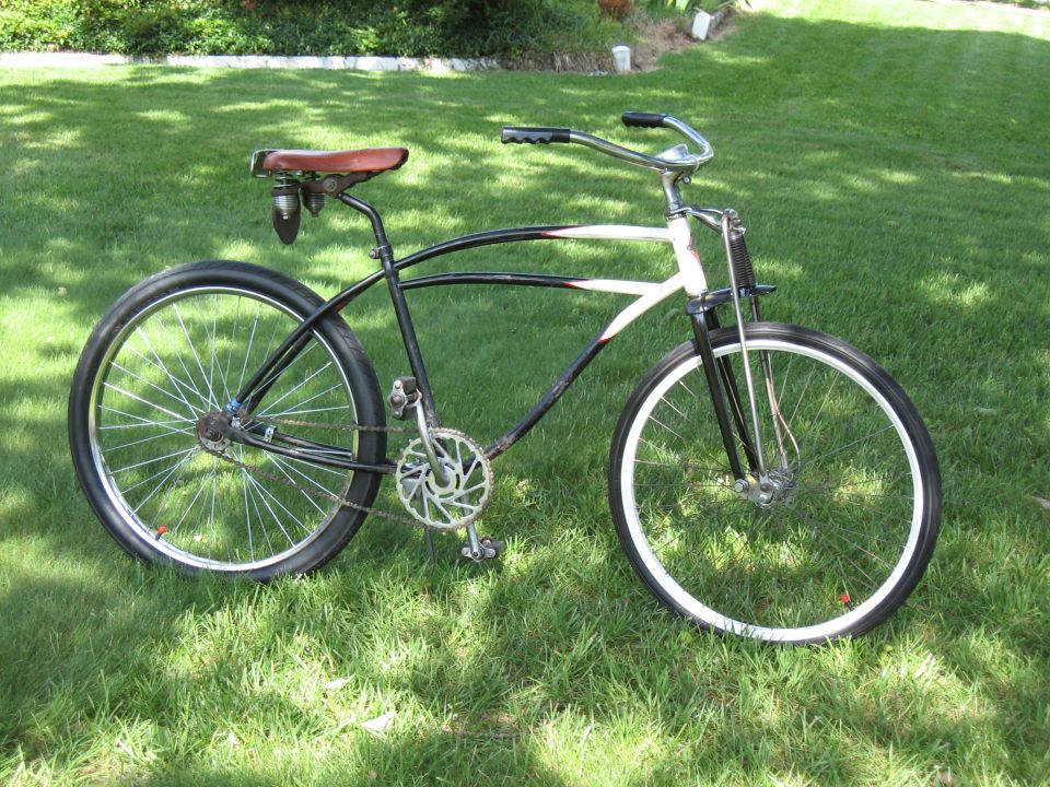 custom cruiser bicycle with black frame, white stripe, brown seat, and chrome handlebars, parked on grass