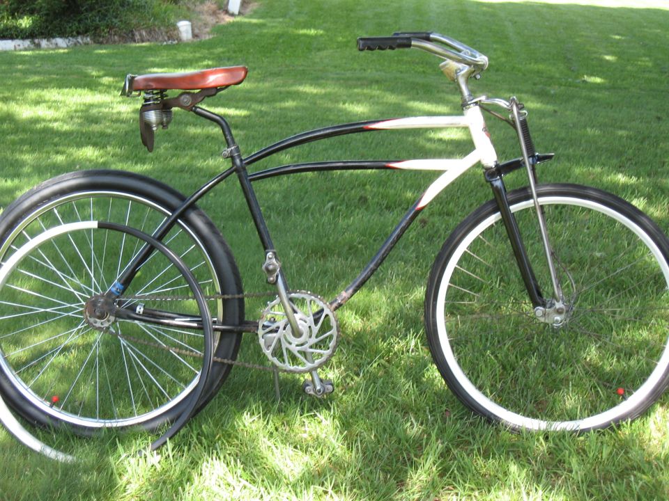 Cruiser bicycle with white rims and a brown leather seat, parked on grass
