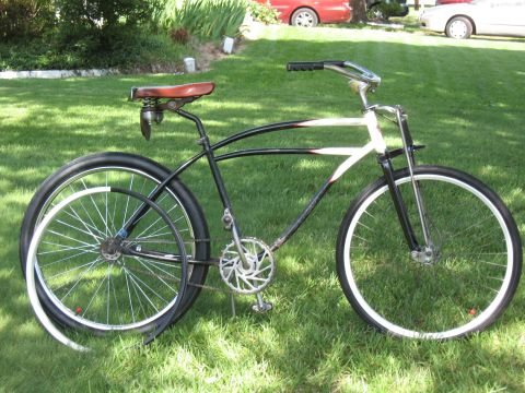 1994 Ford Bronco - A vintage-style cruiser bicycle is parked on a grassy lawn with two cars visible in the background.