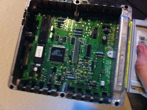 1992 Ford F-150 - An opened Ford EEC engine control module lying on a light tabletop with its finned aluminum lid removed, exposing the green circuit board,…