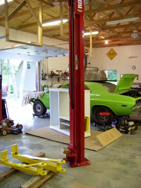 1974 Dodge Challenger - A bright green 1974 Dodge Challenger is parked in a garage with its trunk open, next to a car lift.