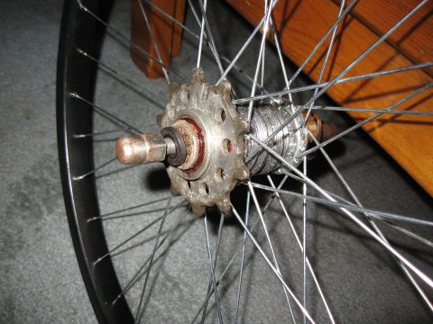 1994 Ford Bronco - This is a close-up view of a bicycle's rear wheel hub, showing the cogset and spokes against a wooden background.