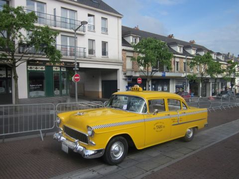 1991 Ford LTD Crown Victoria - A classic yellow taxi cab, likely from the mid-1950s, is parked on a European street.