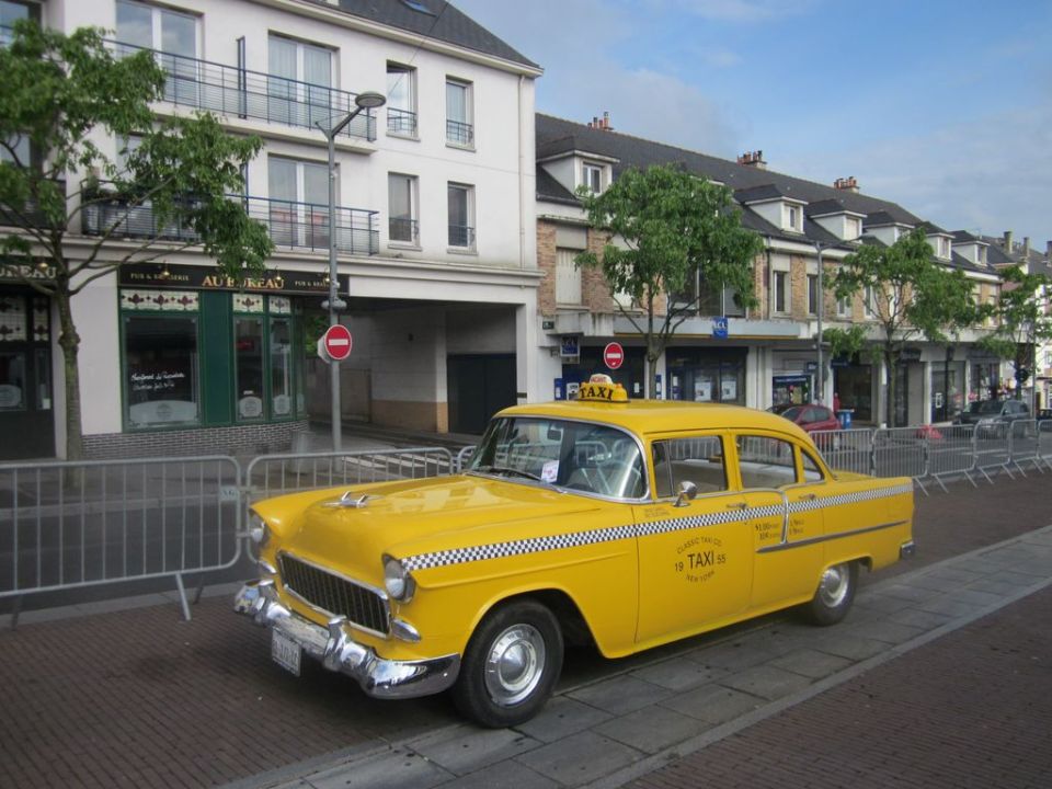 Yellow 1955 taxi cab with checkerboard stripe and taxi sign