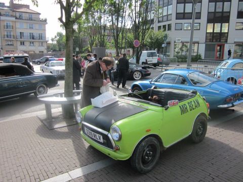 1991 Ford LTD Crown Victoria - A man examines papers on the hood of a custom lime green Mini Cooper with a Union Jack flag and 'MR BEAN' text.