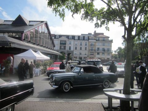 1991 Ford LTD Crown Victoria - Several classic cars are parked on a street in front of buildings and tents.