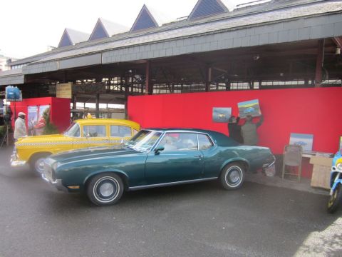 1991 Ford LTD Crown Victoria - A vintage green coupe and a yellow taxi are parked side-by-side outdoors.