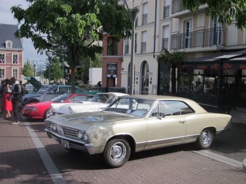 1991 Ford LTD Crown Victoria - A gold 1966 Chevrolet Chevelle Malibu coupe is parked on a street with other cars visible in the background.