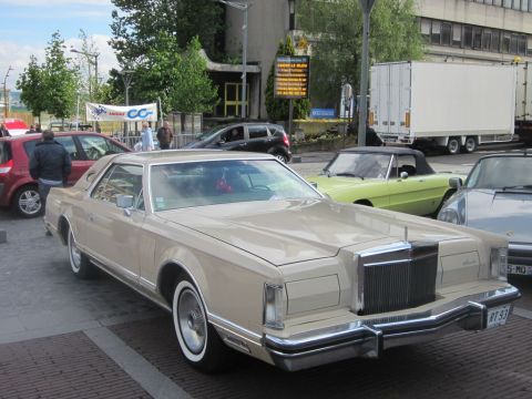 1991 Ford LTD Crown Victoria - A classic Lincoln Continental Mark V is parked on a street, with a light green convertible and a red hatchback nearby.