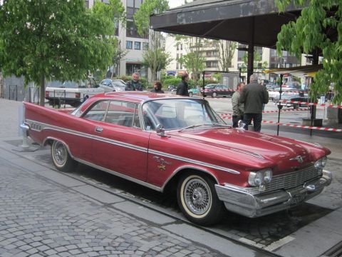 1991 Ford LTD Crown Victoria - A classic red Chrysler New Yorker coupe, likely from 1960, is parked on a cobblestone street.