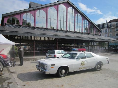 1991 Ford LTD Crown Victoria - This police car, likely from the late 1970s, is parked outside a market building. A second vehicle is visible behind it.