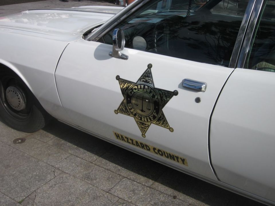 White police car door with a gold sheriff's star badge and 'HAZZARD COUNTY' text