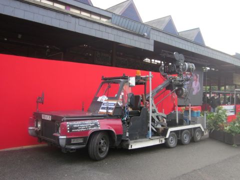 1991 Ford LTD Crown Victoria - This custom camera vehicle is equipped with a crane and filming equipment, parked in front of a red wall.