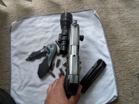 2000 Mercury Grand Marquis - A handgun with an attached tactical flashlight, a folding knife, and loose ammunition are laid out on a white towel.