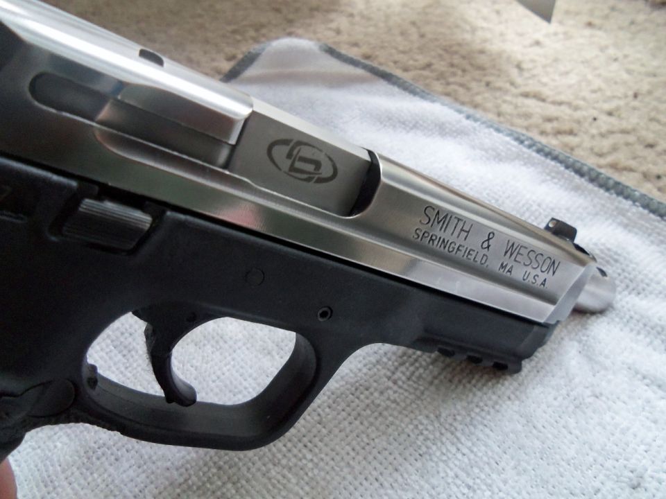 Silver and black Smith & Wesson pistol slide with engraved logo and text, resting on a cloth