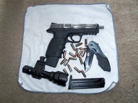 2000 Mercury Grand Marquis - A collection of firearm accessories including a pistol, ammunition, knife, and flashlight are displayed on a cloth.