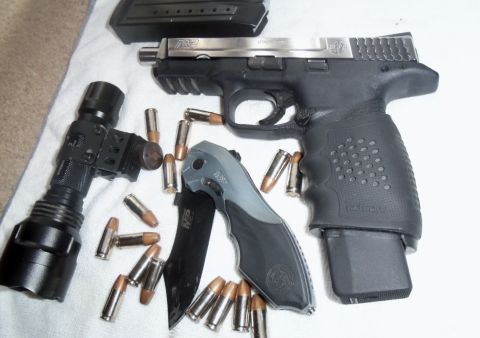 2000 Mercury Grand Marquis - A handgun, knife, flashlight, and ammunition are laid out on a white cloth.