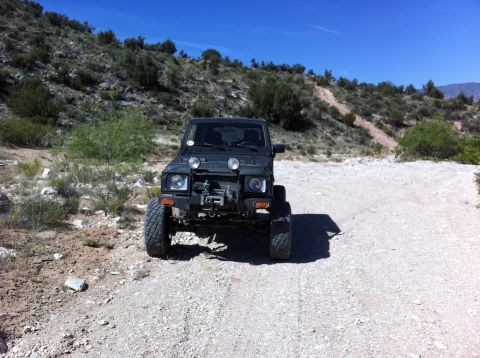 1987 Suzuki Samurai - Suzuki Samurai parked on a dirt road with hills and scrub brush in the background.