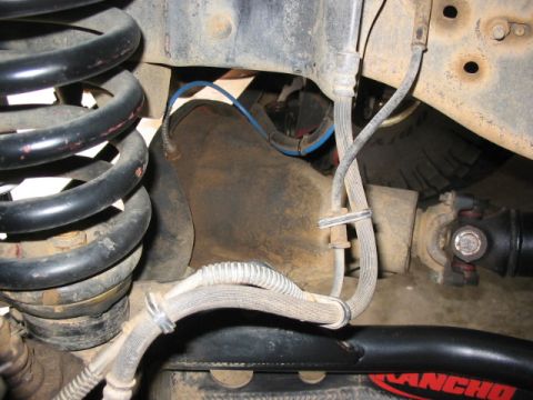 1995 Ford Bronco - Close-up view of a vehicle's undercarriage, showing suspension components and a driveshaft.