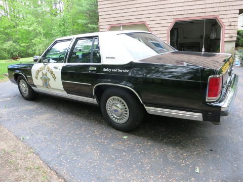 1991 Ford LTD Crown Victoria - Black-and-white Highway Patrol sedan shown from the driver rear quarter, with door star and Safety and Service lettering.