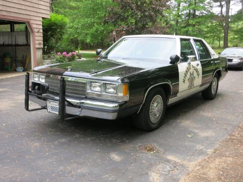 1991 Ford LTD Crown Victoria - Front three-quarter view of a black-and-white Highway Patrol sedan with stacked headlights, push bar, and door star.