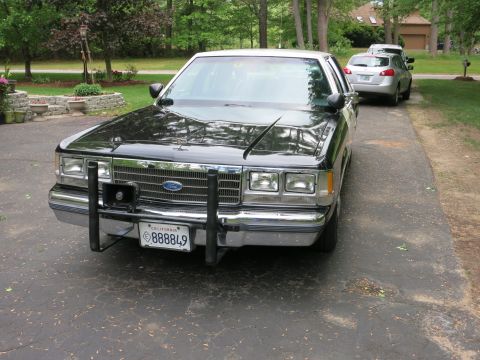 1991 Ford LTD Crown Victoria - Front view of a black Ford sedan with a steel push bumper, Ford-emblem grille, and a California 888849 plate in a driveway.