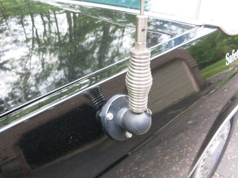 1991 Ford LTD Crown Victoria - Close-up of a coiled spring-base whip antenna mounted on the black bodywork of a car near a body-side molding.