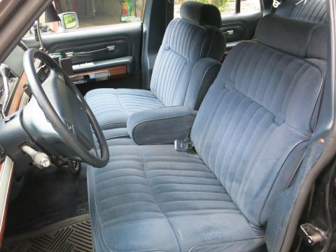 1991 Ford LTD Crown Victoria - Blue cloth front split-bench seat of a sedan with steering wheel, woodgrain door trim and rubber floor mats.